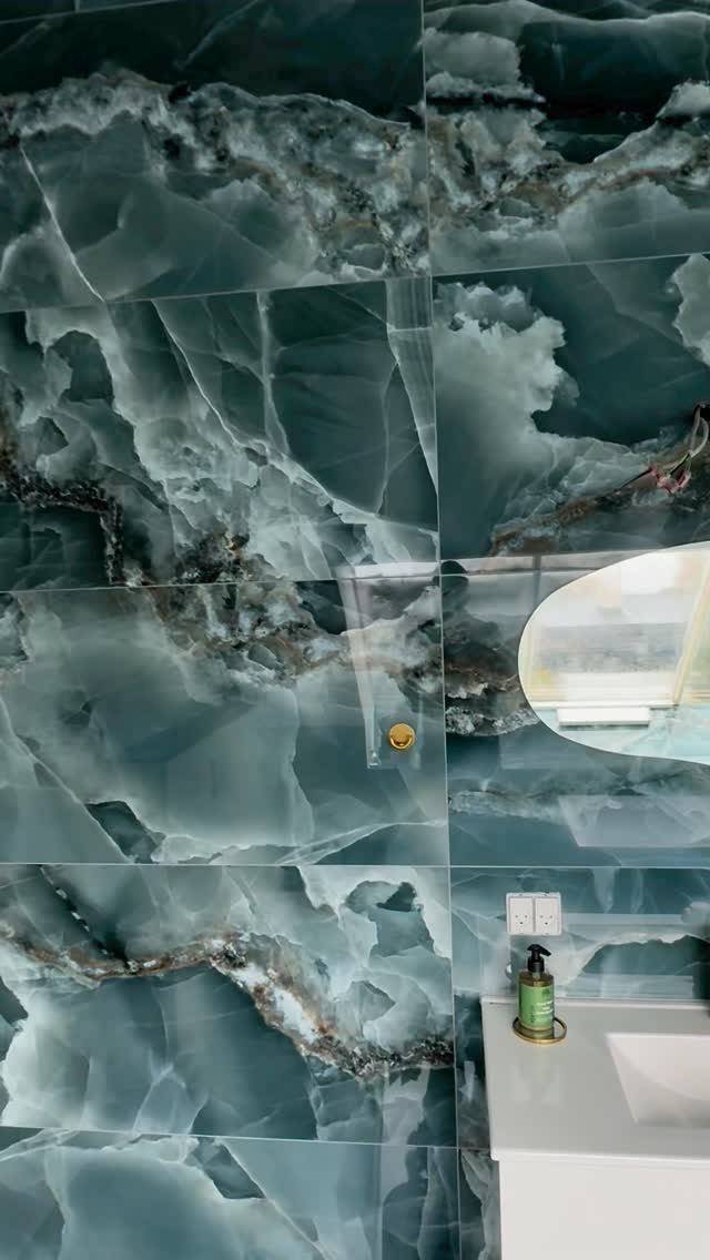 Badeværelsesvæg i grønne onyx-fliser med detaljer i guld