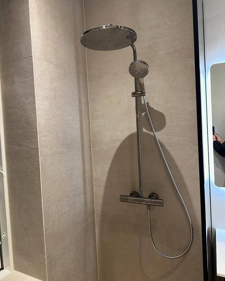 Bruseniche med store grå fliser og krom bruser
